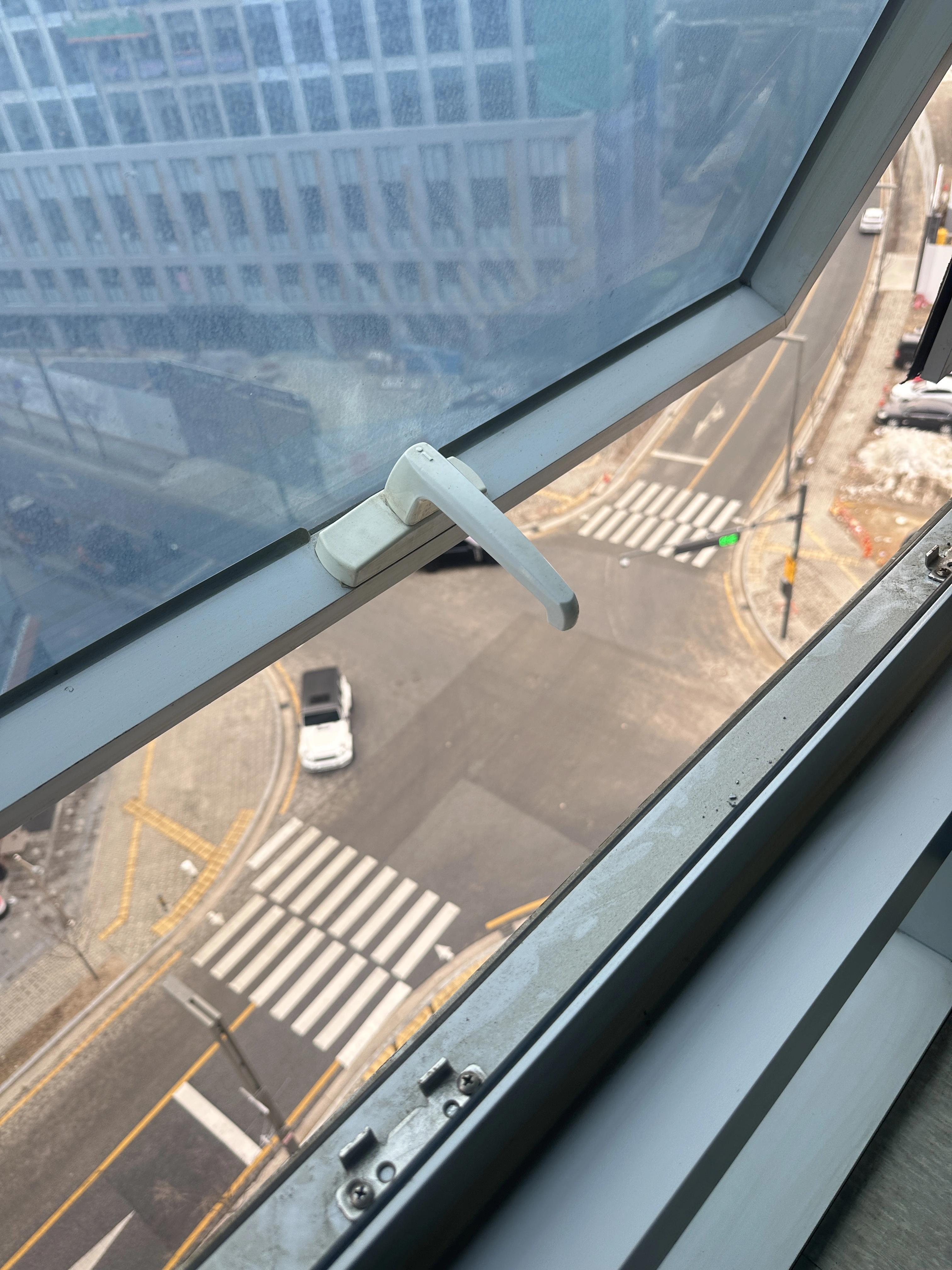 횡단보도가 내려다보이는 창문의 손잡이와 힌지
