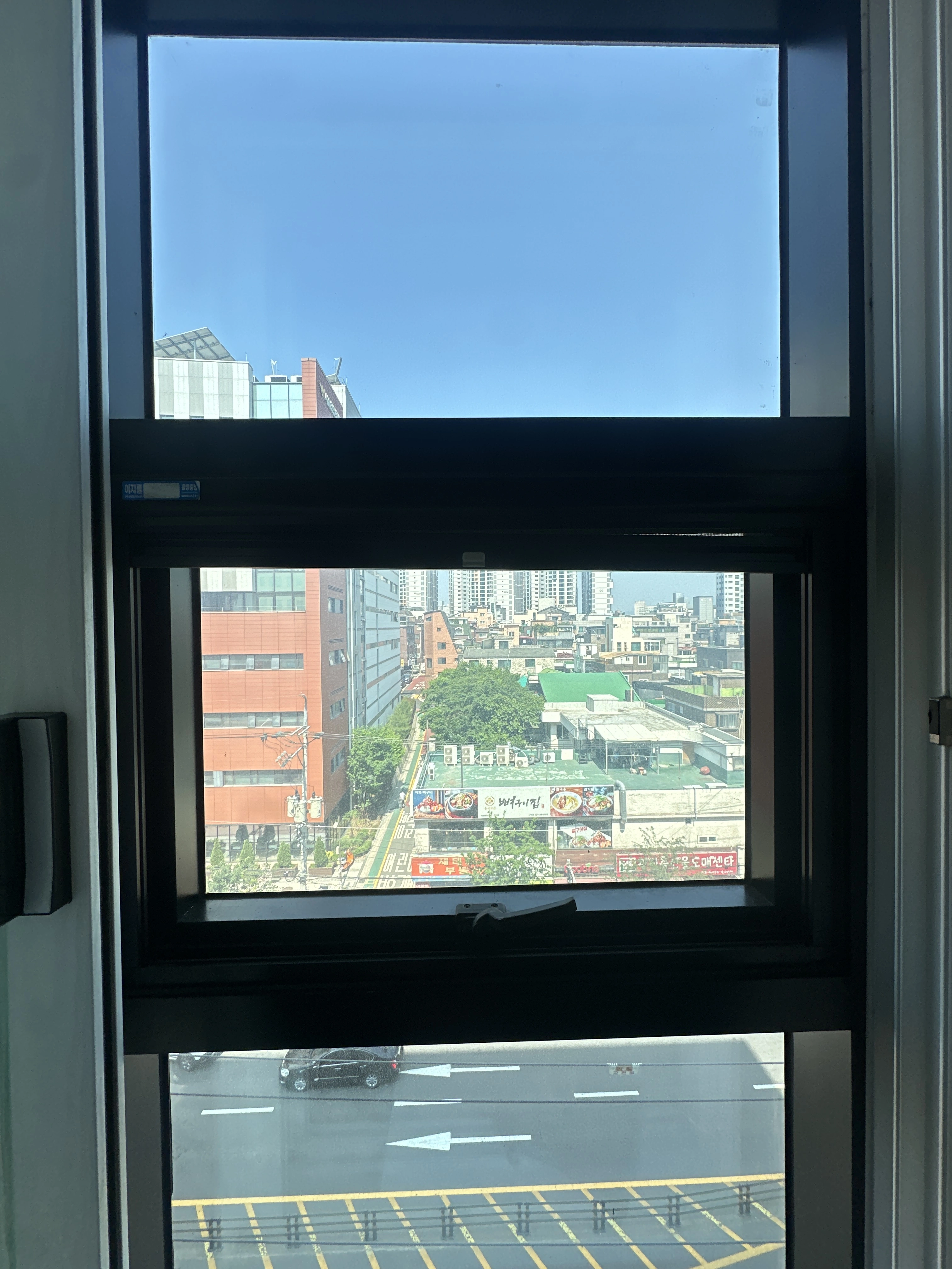 닫힌 상태의 창문 너머로 보이는 도로와 어두운 프레임