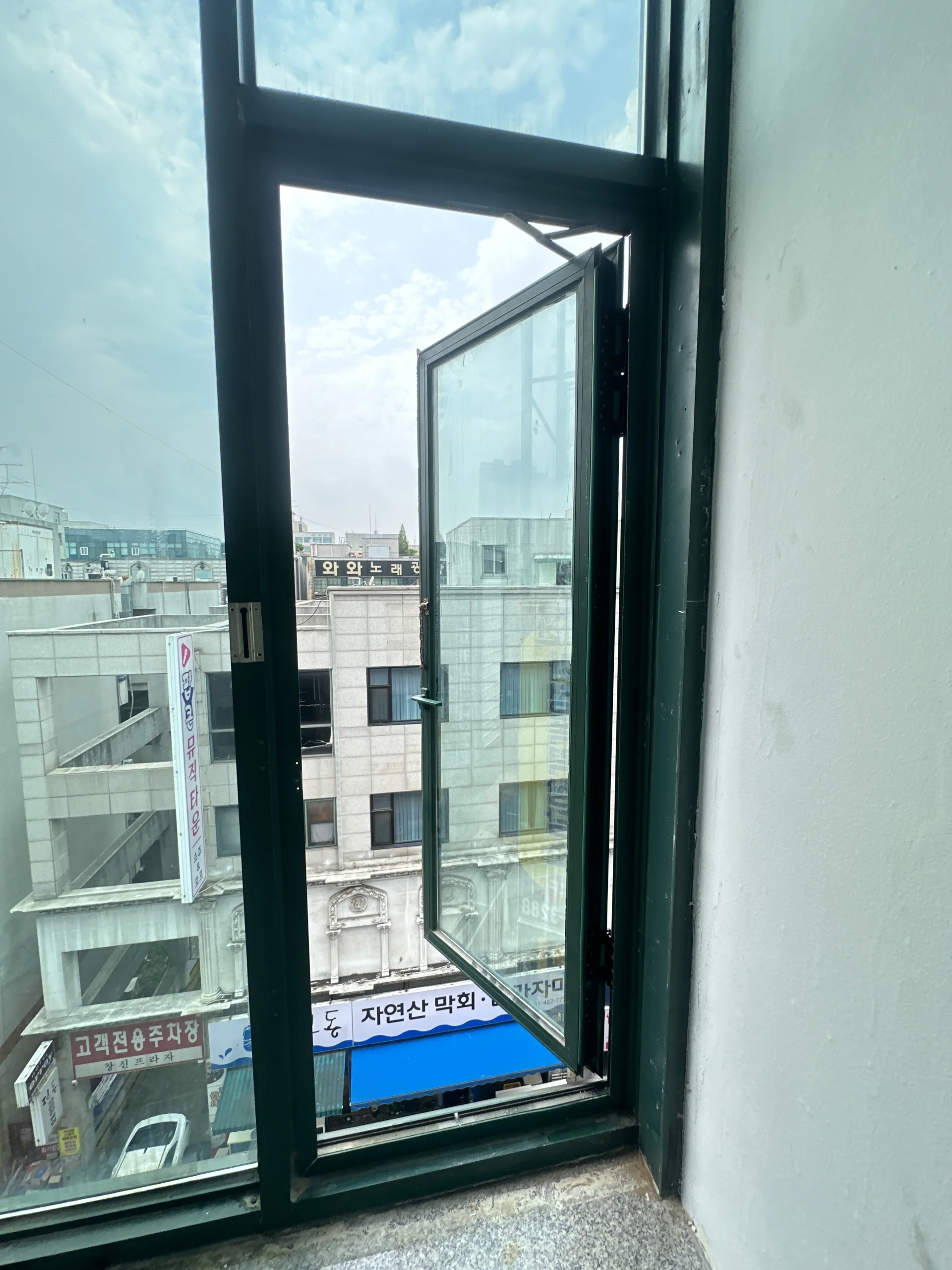완전히 개방된 검은 프레임 캐시먼트창문 너머로 보이는 상업지구 거리
