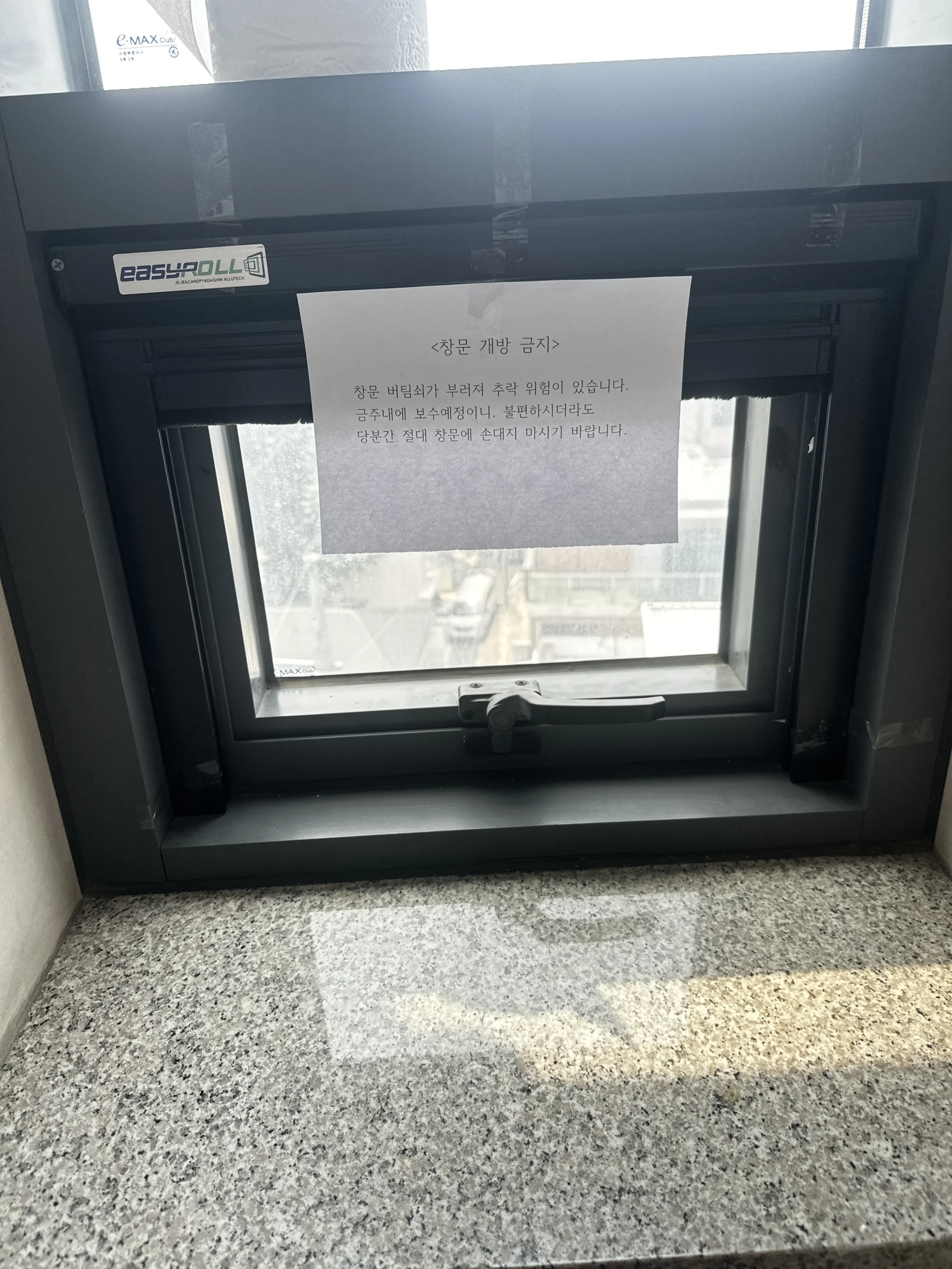 실내 대리석 바닥 위 닫힌 창문에 붙은 개폐 금지 안내 스티커