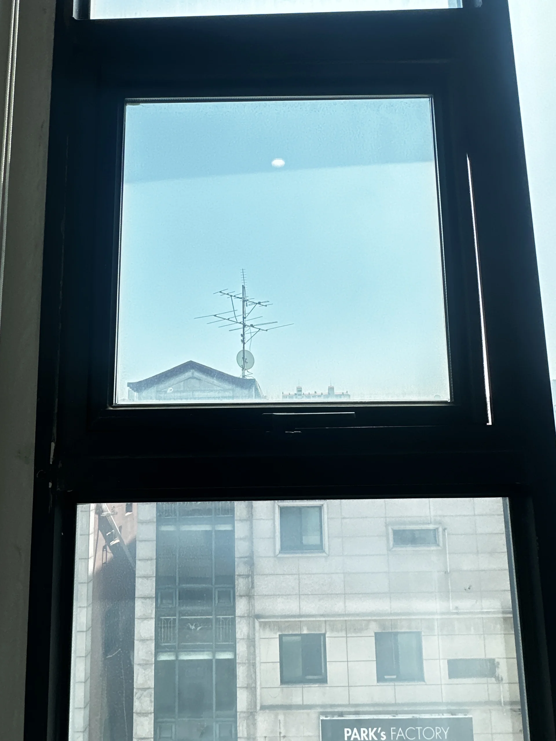 닫힌 상태의 창문 너머로 보이는 건물 외벽