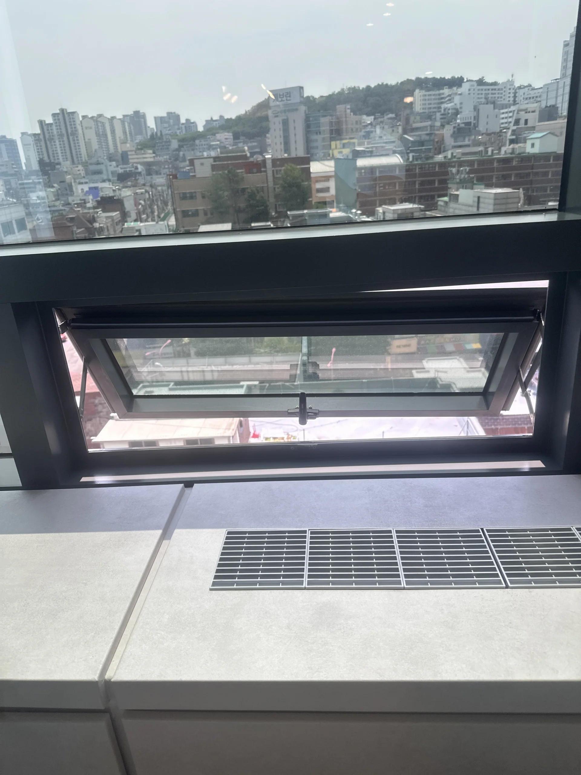 타일 마감된 창틀 위로 개방된 창문과 환기구