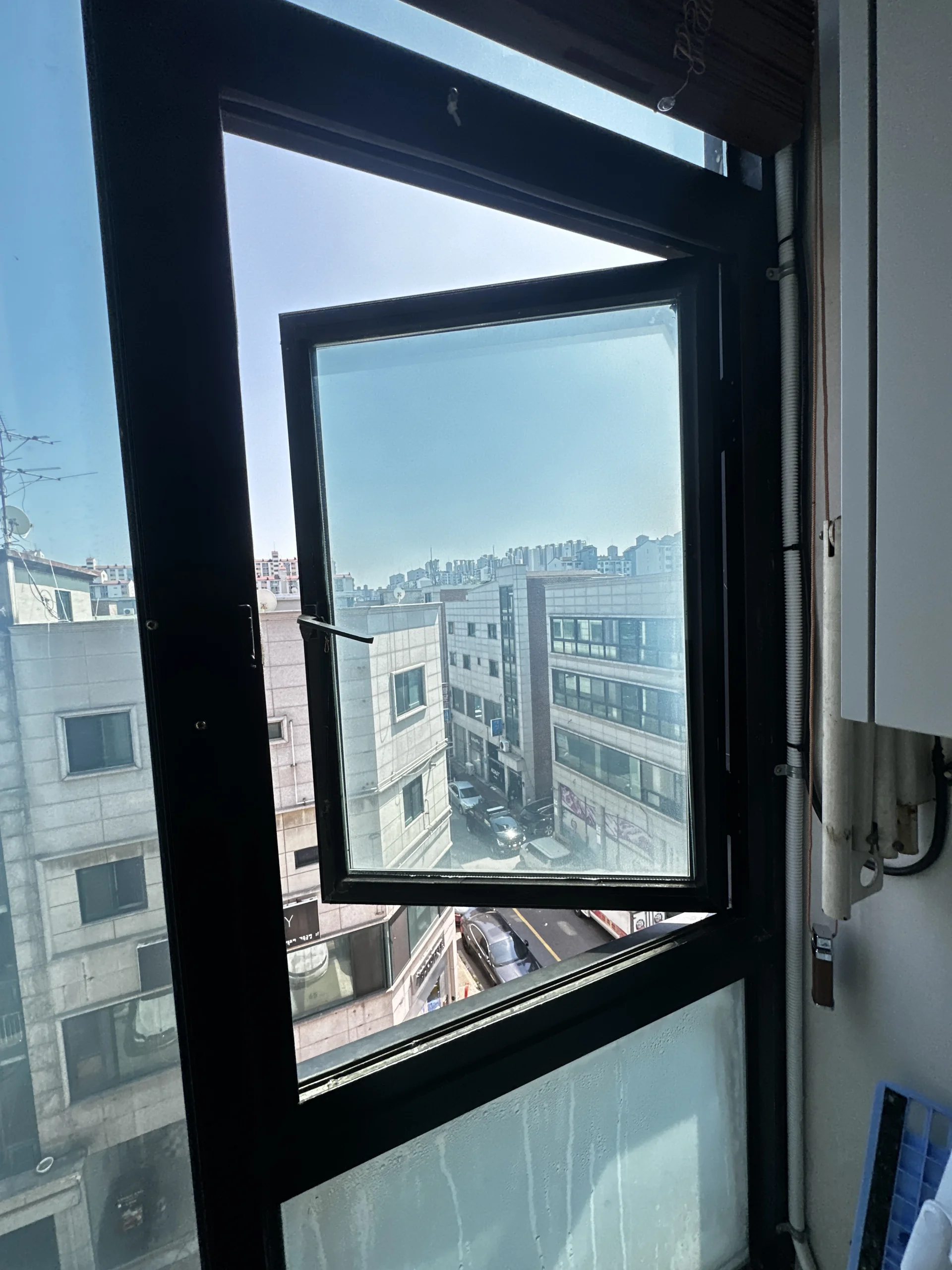 완전히 개방된 검은색 프레임 프로젝트창 너머로 보이는 도심 건물
