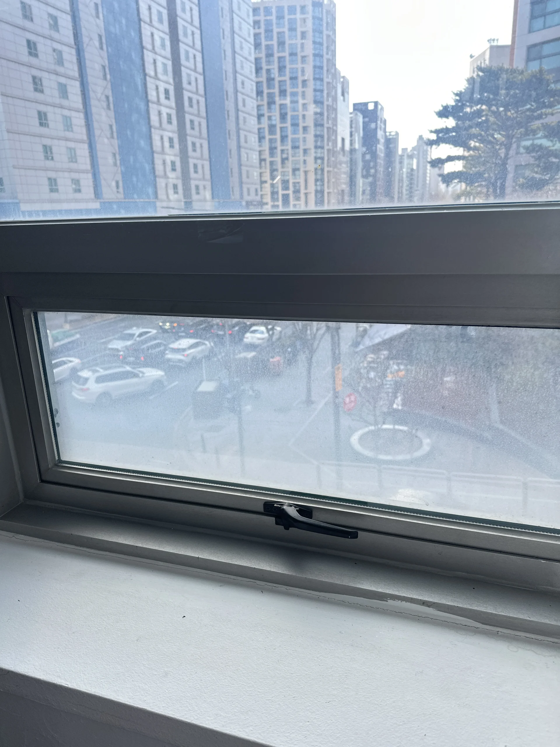 고층에서 열린 캐시먼트창문 사이로 보이는 도심 고층 빌딩 전경